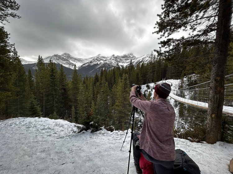 Man setting up a camera and tripod to take a picture of distant mountains
